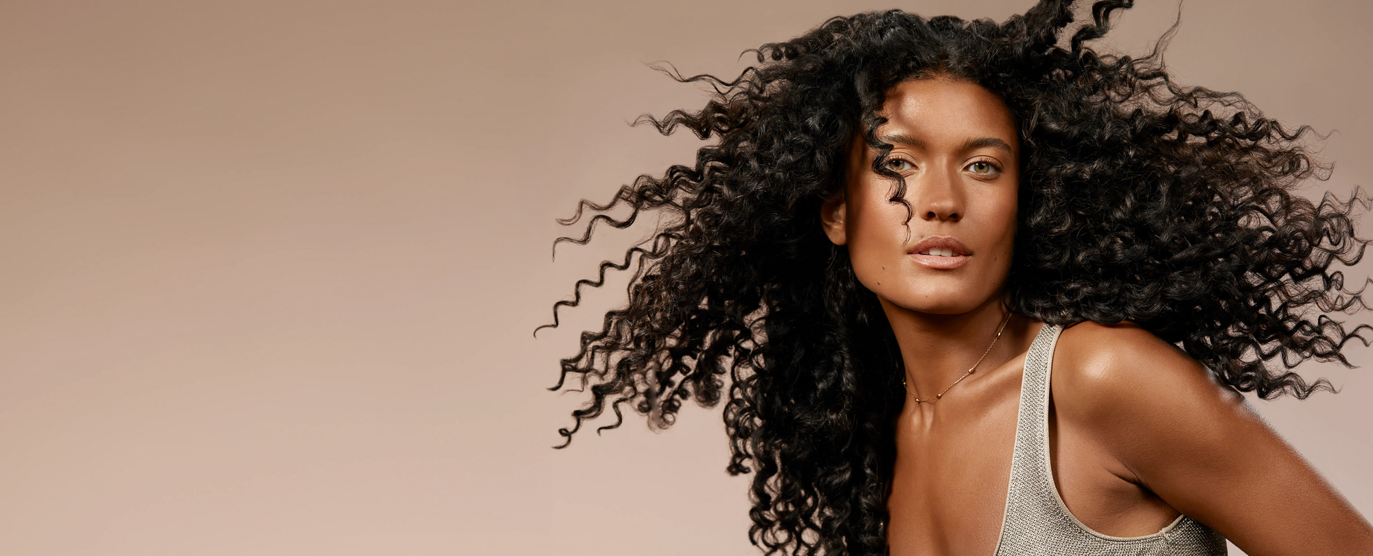 Woman with voluminous curly hair against a beige background